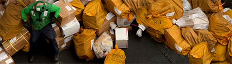 man holding up piles of mail bags